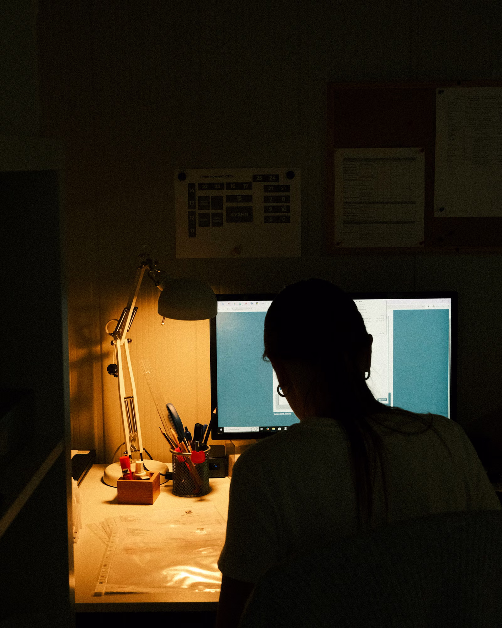 A designer working at a computer in a dimly lit studio